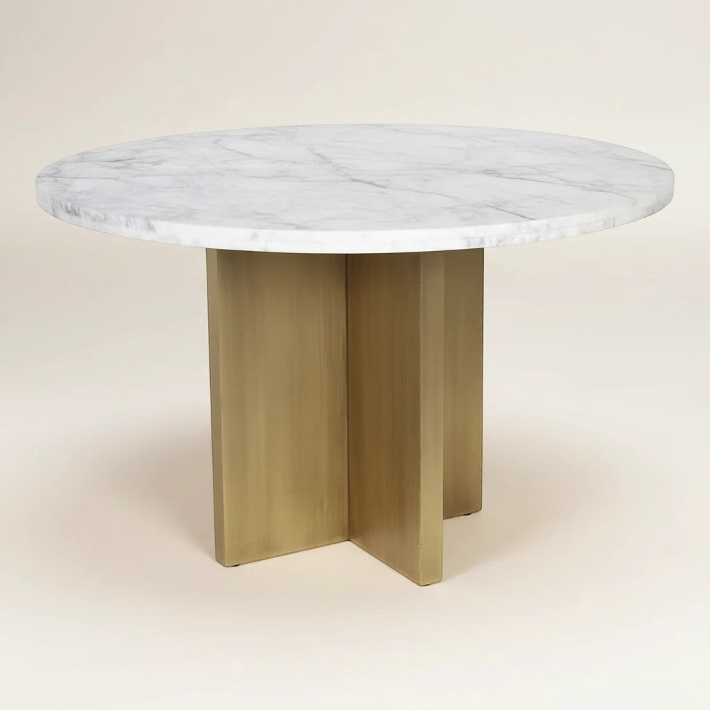 Trộm vía round white marble dining table with unique veining and a brushed gold pedestal base with a cross-leg design.